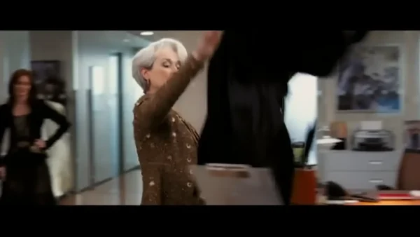 アシスタントのデスクに無数のコートやバッグを投げ捨てるミランダ