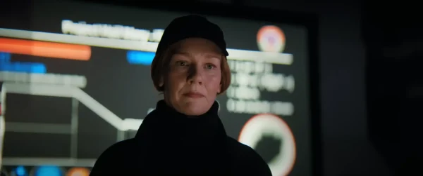 薄暗い巨大な作戦指令室で、世界中の科学者や軍人を前に、感情を殺した冷徹な表情で決断を下すプロジェクト責任者エヴァ・ストラットの姿