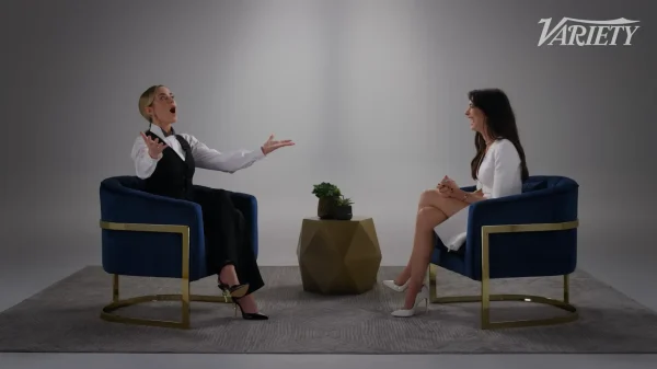 向かい合って対談し、笑顔を見せるエミリー・ブラントとアン・ハサウェイ