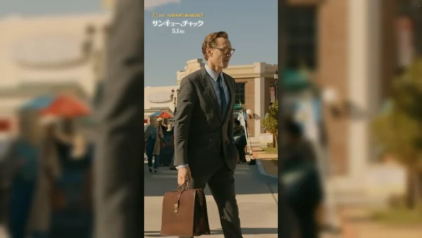 グレーのスーツを着てブリーフケースを持ち、街角に佇むチャック（トム・ヒドルストン）